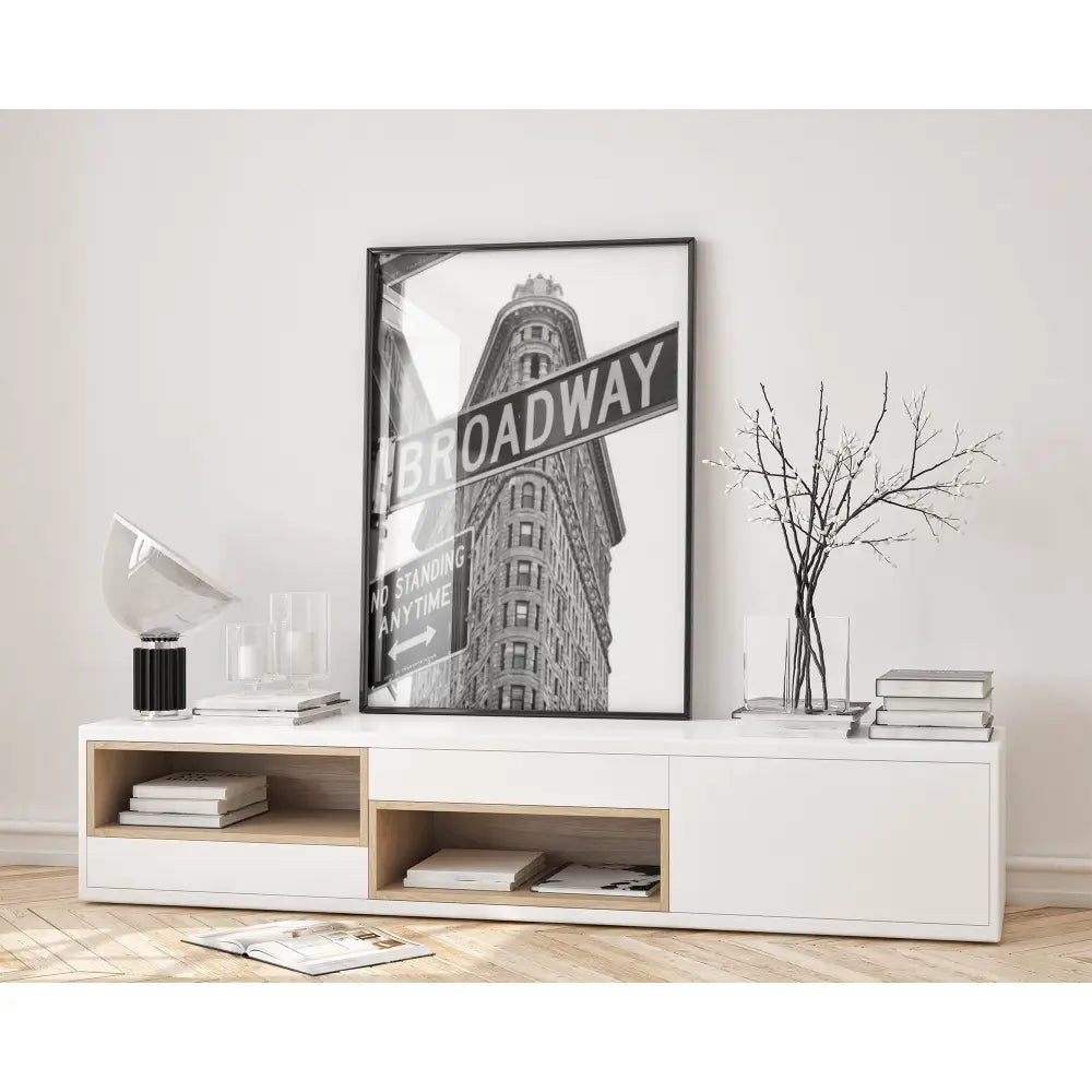 Modern living room with a white console table, books, and a framed 'BROADWAY' poster.