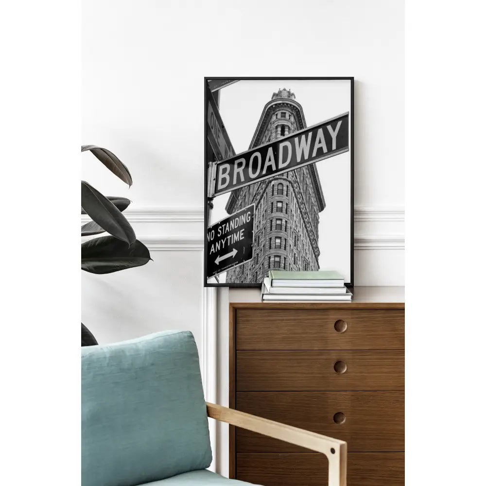 Framed artwork of a street sign on a wall above a wooden dresser.