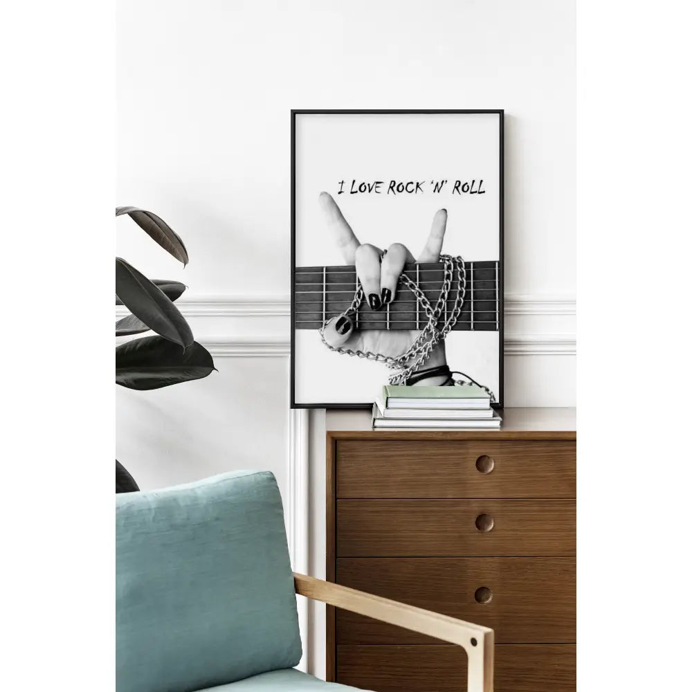 Framed poster with 'I Love Rock N Roll' text on a wall above a wooden dresser.