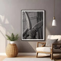 Framed black and white artwork above a chair in a living room setting.