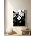 Framed artwork of a hand holding a Chanel perfume bottle on a wall in a modern interior setting.