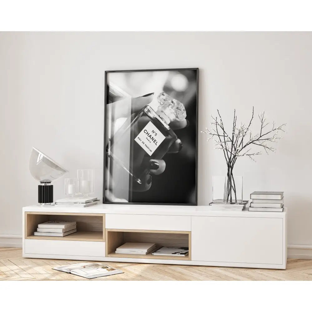 Framed black and white photo of a Chanel perfume bottle on a wall above a white console table.