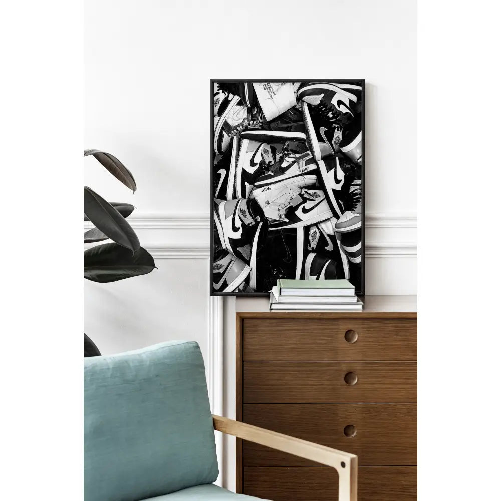 Abstract black and white artwork on a wall above a wooden dresser with decorative items.