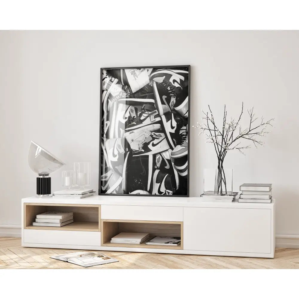 Abstract black and white artwork on a wall above a white console table with books and decor.