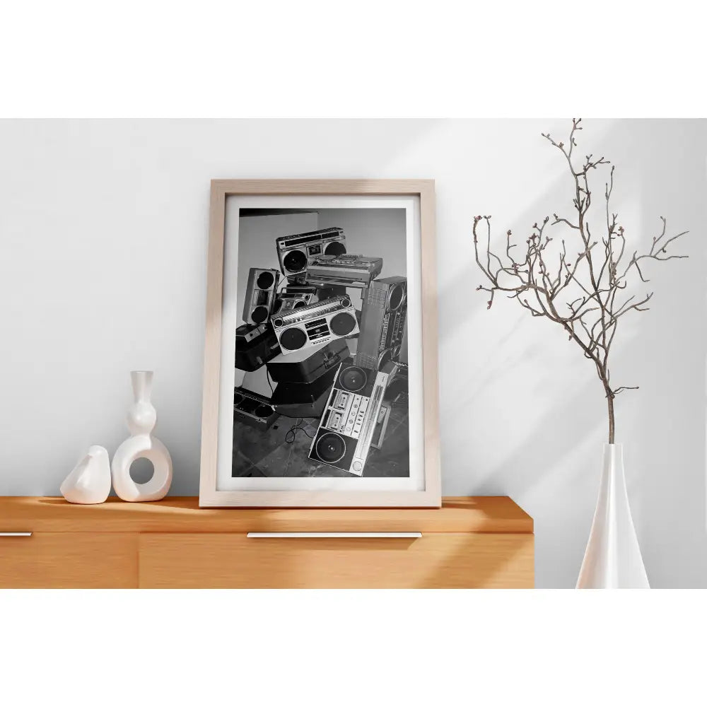 Framed black and white art print of vintage radios on a wooden cabinet.