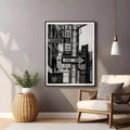 Framed black and white cityscape print on a wall above a chair and side table.