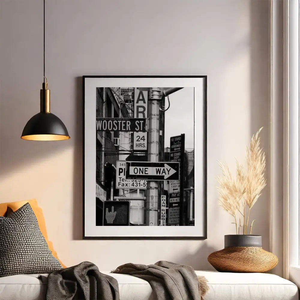 Framed black and white cityscape print on a wall above a sofa with decorative elements.