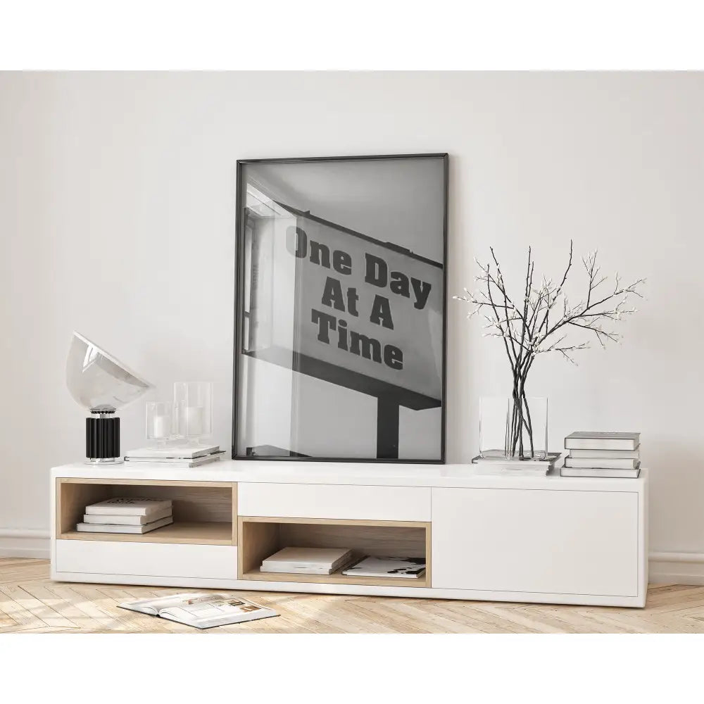 Modern living room with a white entertainment console, books, and a framed quote on the wall.
