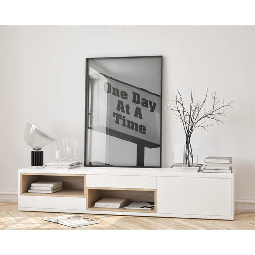 Modern living room with a white entertainment console, books, and a framed quote on the wall.