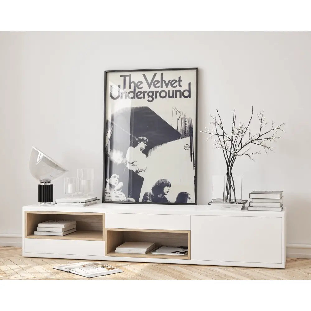 Modern living room with a white console table, books, and a 'The Velvet Underground' poster.
