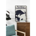 Framed 'The Velvet Underground' album cover above a wooden dresser with a blue cushion.