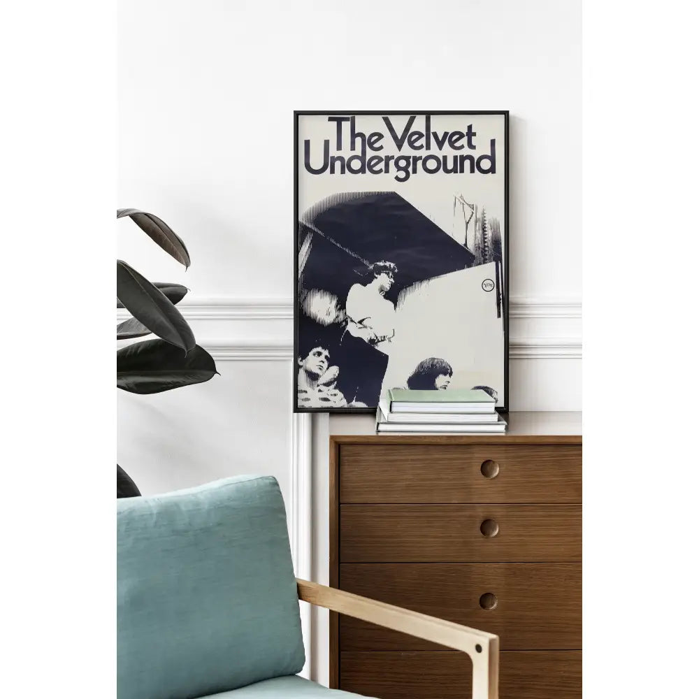 Framed 'The Velvet Underground' album cover above a wooden dresser with a blue cushion.
