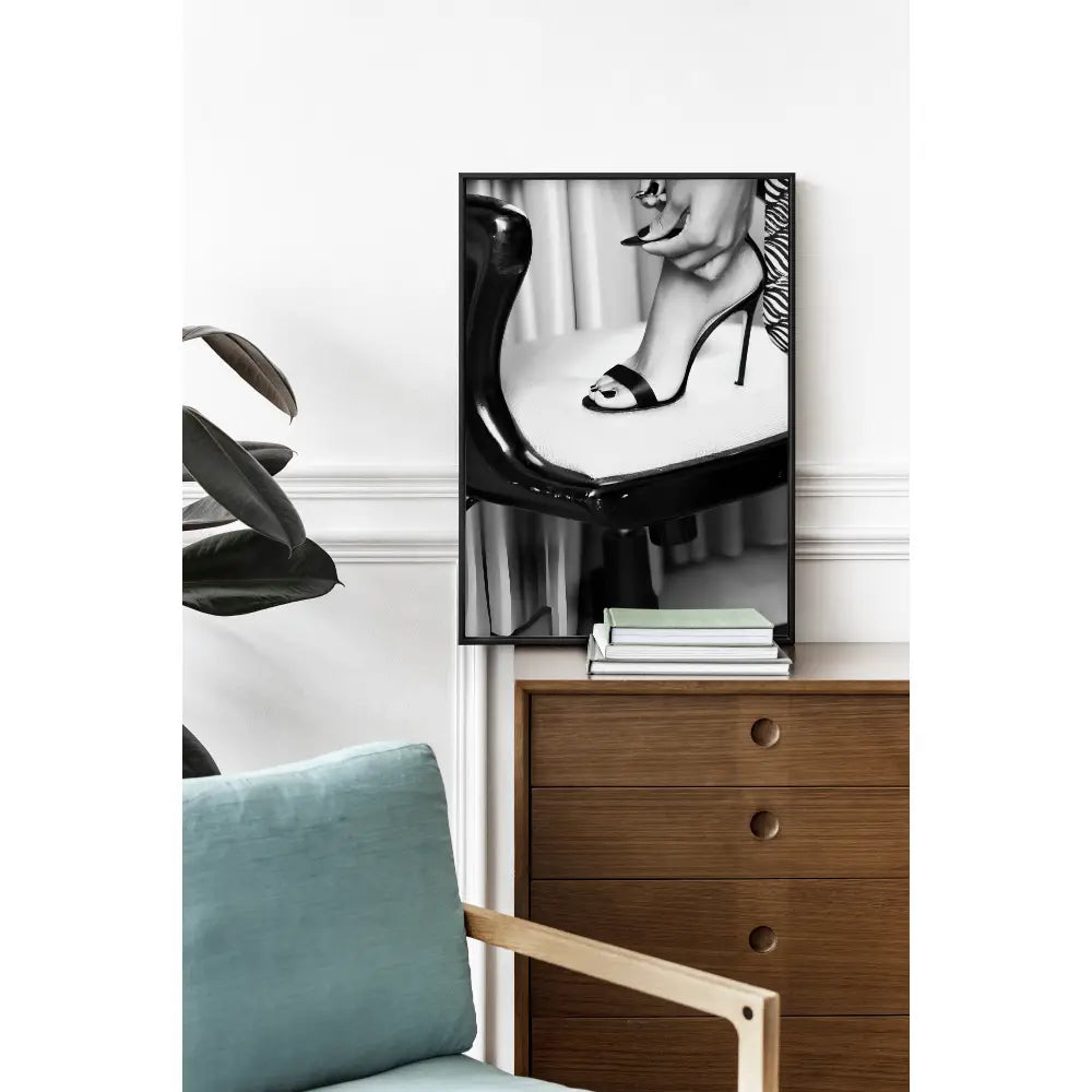 Framed black and white art print of high-heeled shoes on a wooden side table.