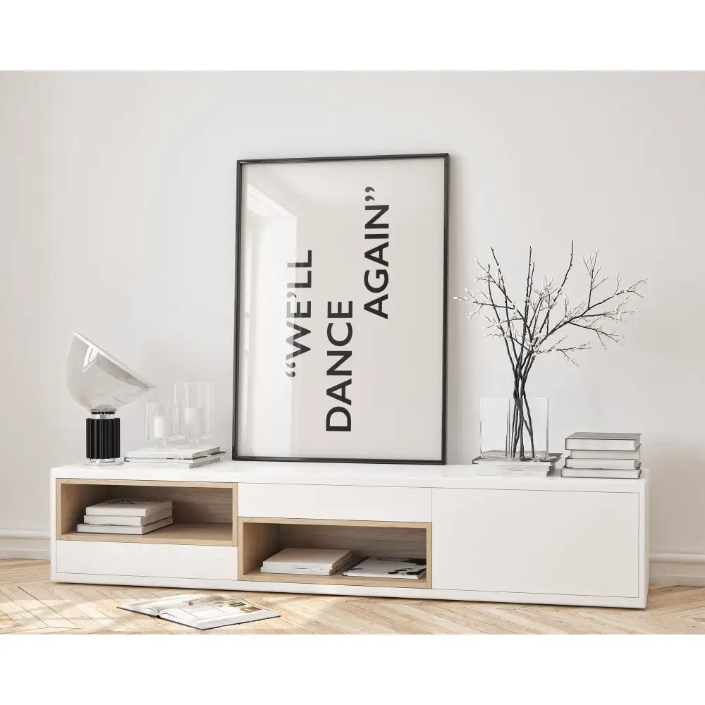 White entertainment console with books, a vase, and a framed poster in a minimalistic room.