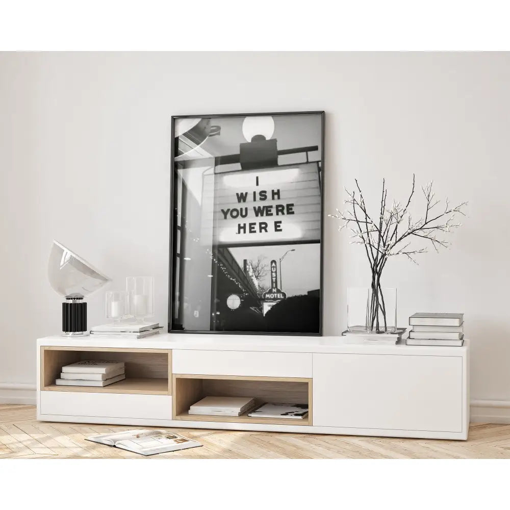 Modern interior with a white console table, books, and a framed picture on a light gray wall.